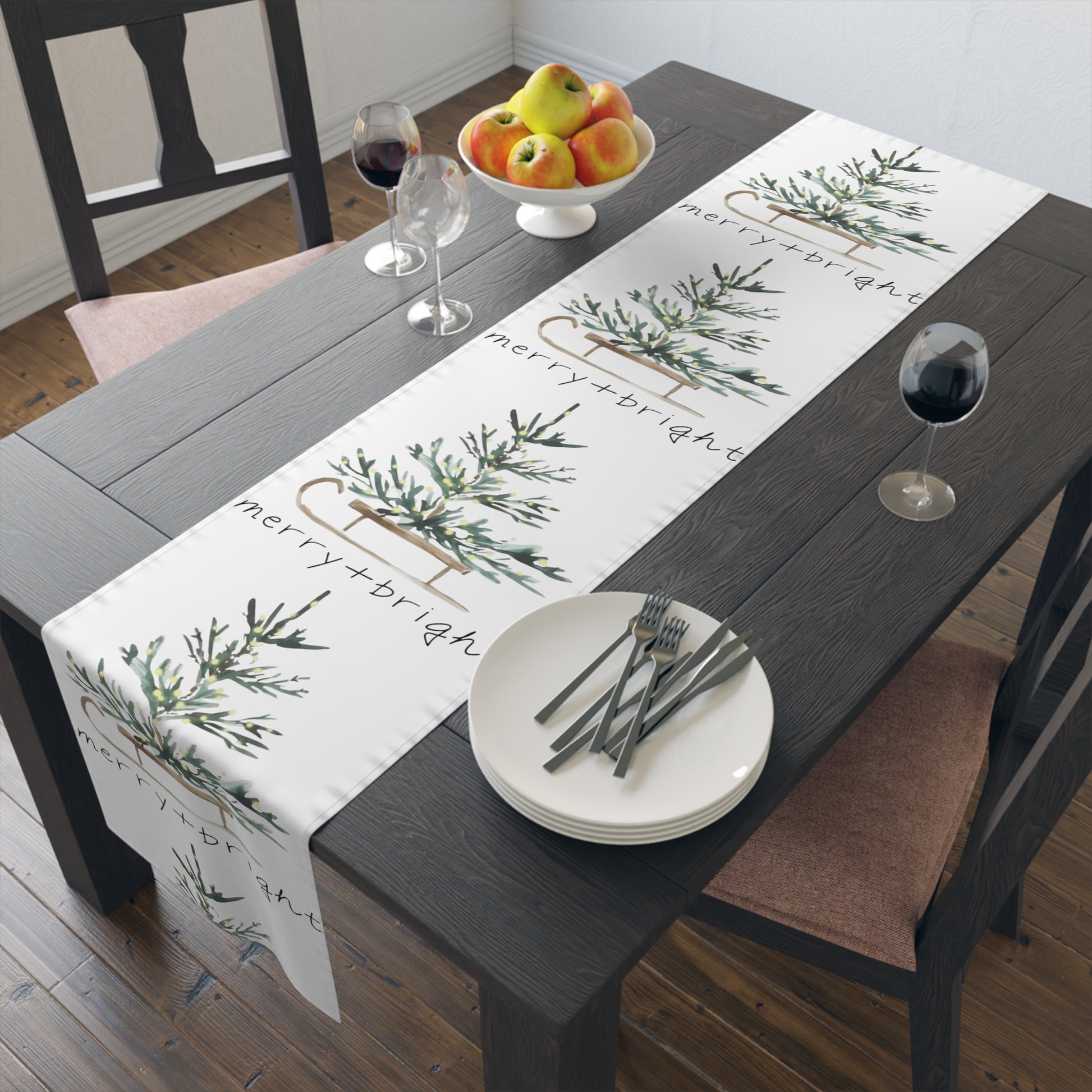 Dining table set with a 'merry+bright' table runner, plates, and cutlery.
