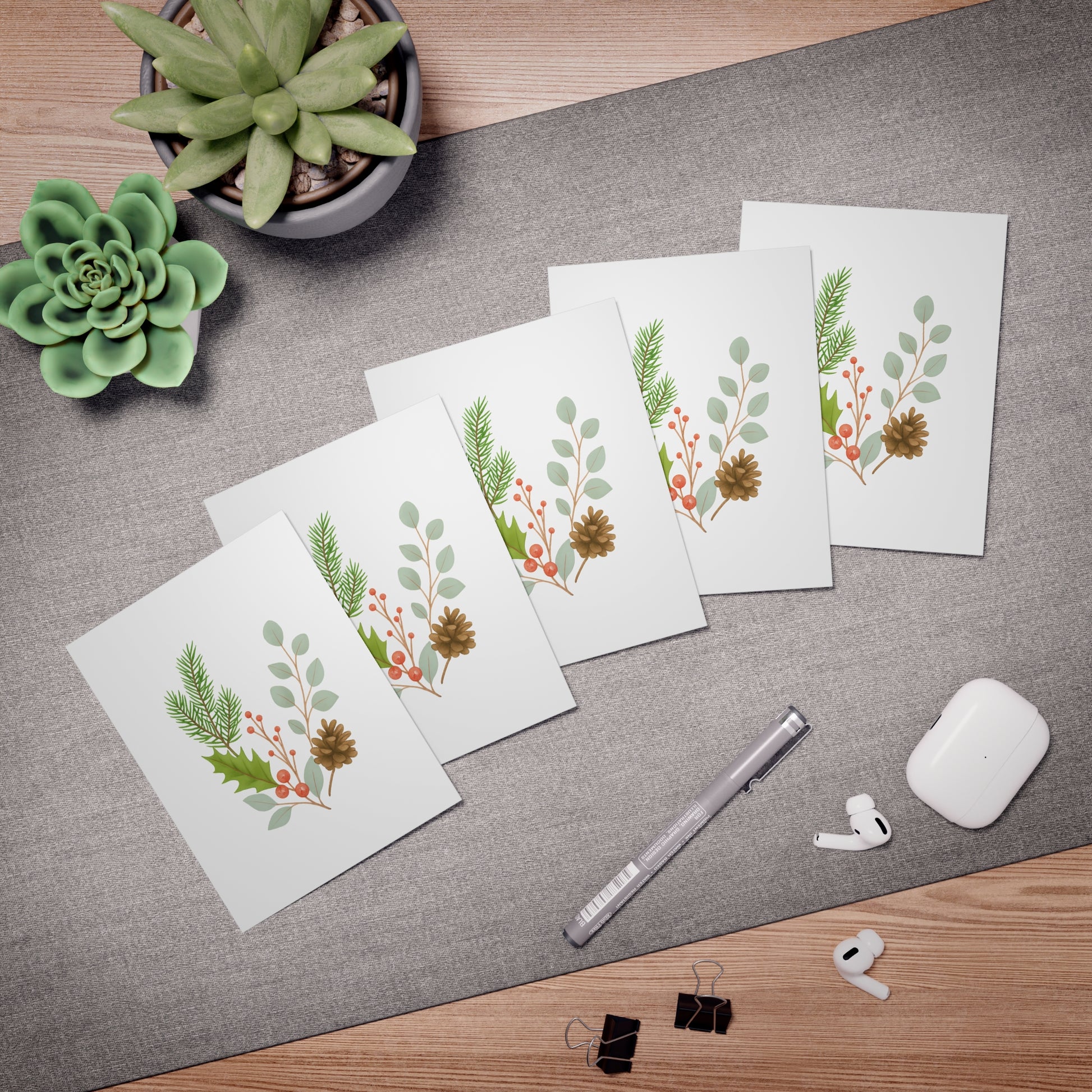 Set of greeting cards with floral designs on a desk with office supplies.